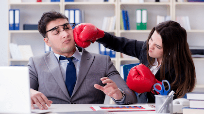 Une employée donne un coupe de poing avec un gant de boxe sur son manager montrant ce qu'il ne faut pas faire pour la gestion de conflits